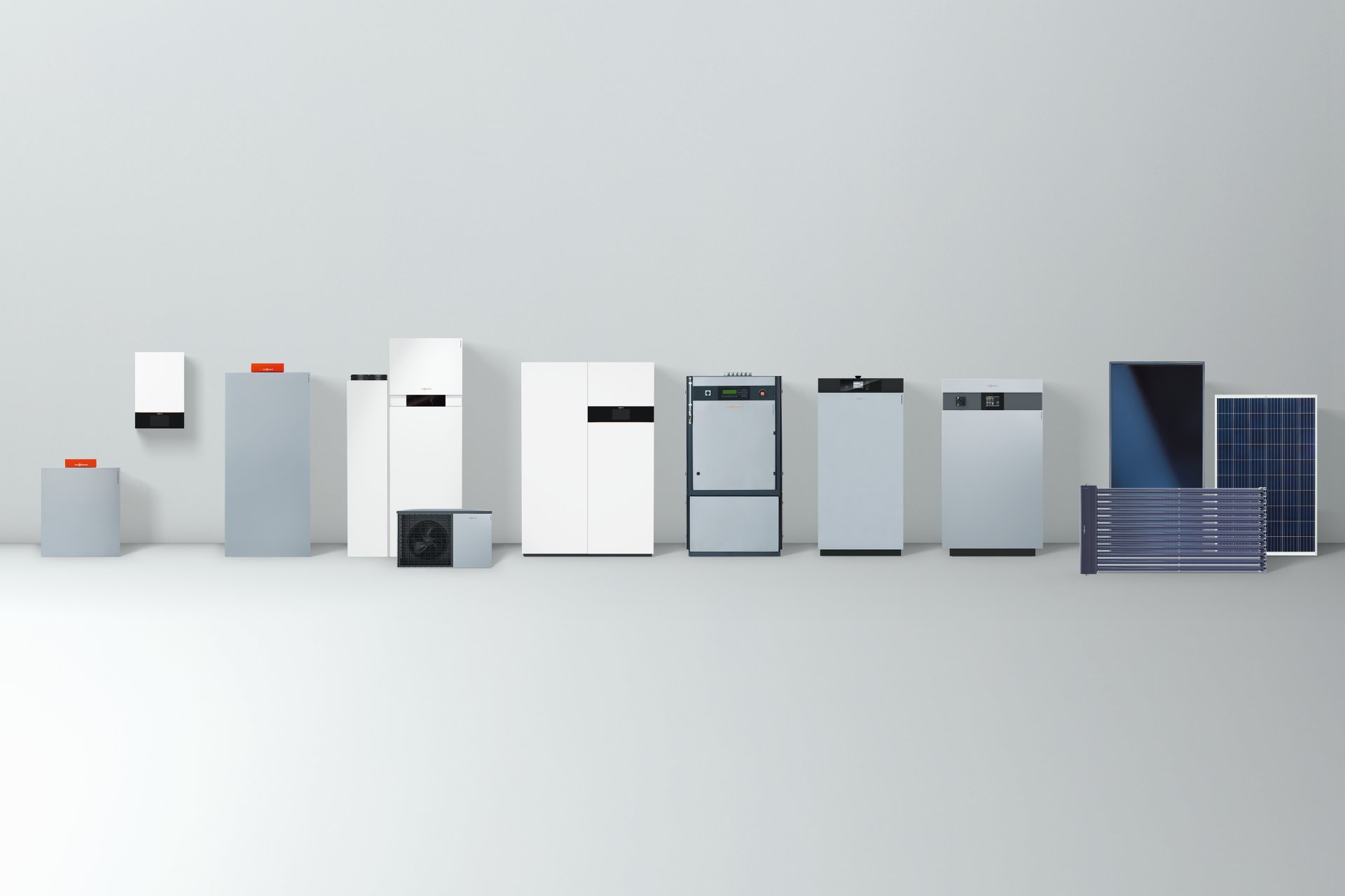 A display of Viessmann residential heating and hot water systems, showcasing various models including boilers, heat pumps, and solar panels, arranged in a row against a light background.